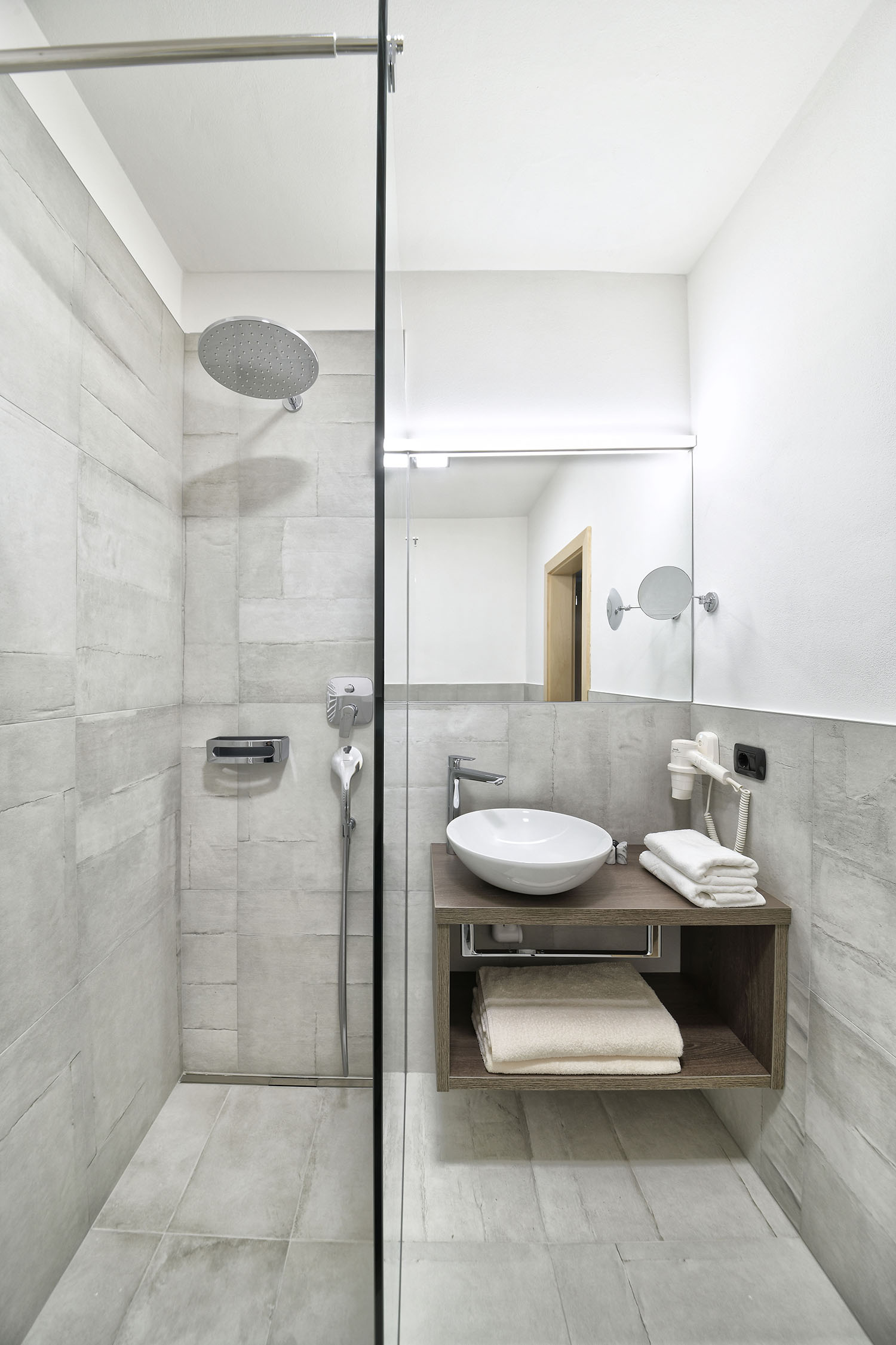 Dusche und Waschbecken mit Spiegel im Badezimmer der Suite Anima - Hotel das stachelburg