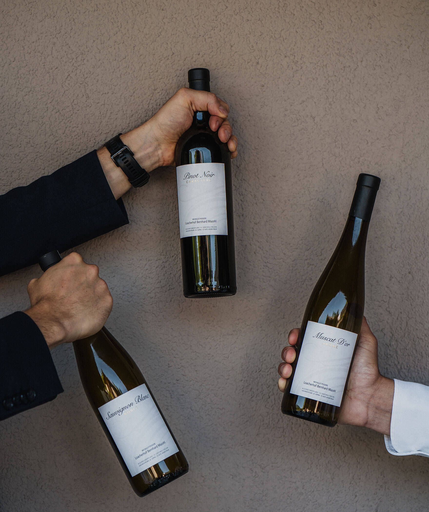 3 Weinflaschen an die Wand gehalten