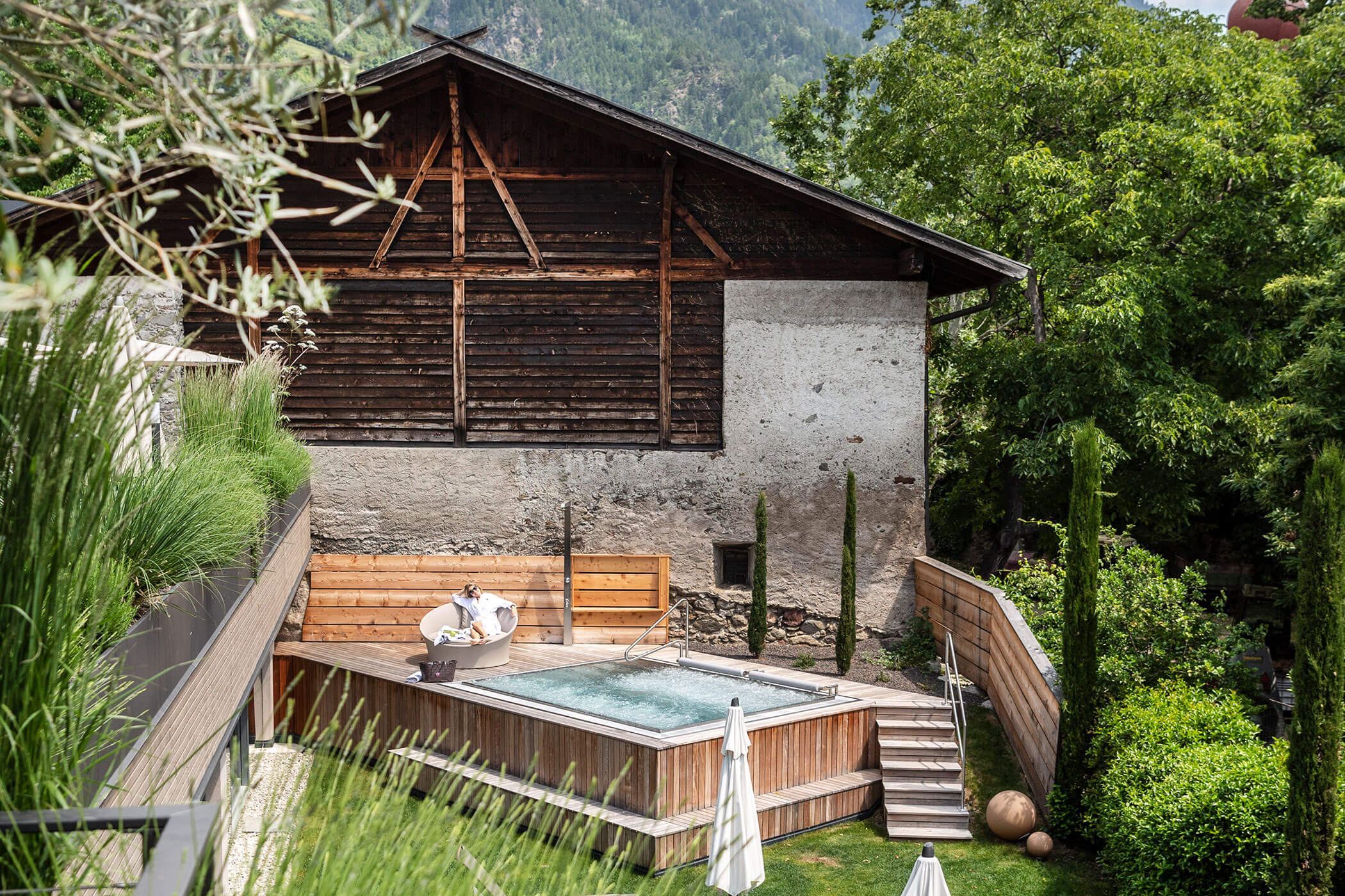 Pool im Garten vor einem Stall im Hintergrund Berge